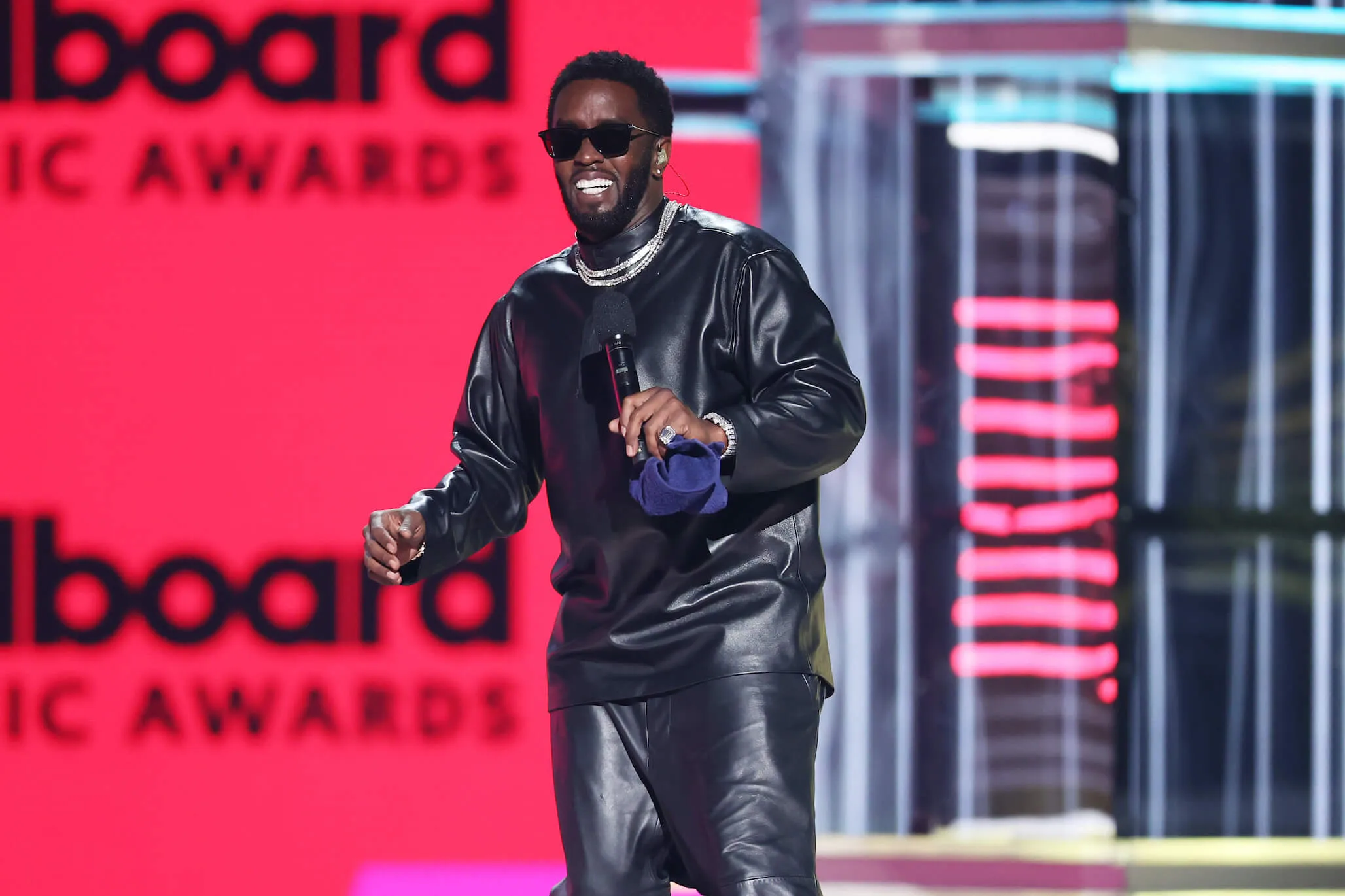 Sean 'P. Diddy' Combs smiling on stage against a red background at the 2022 Billboard Music Awards