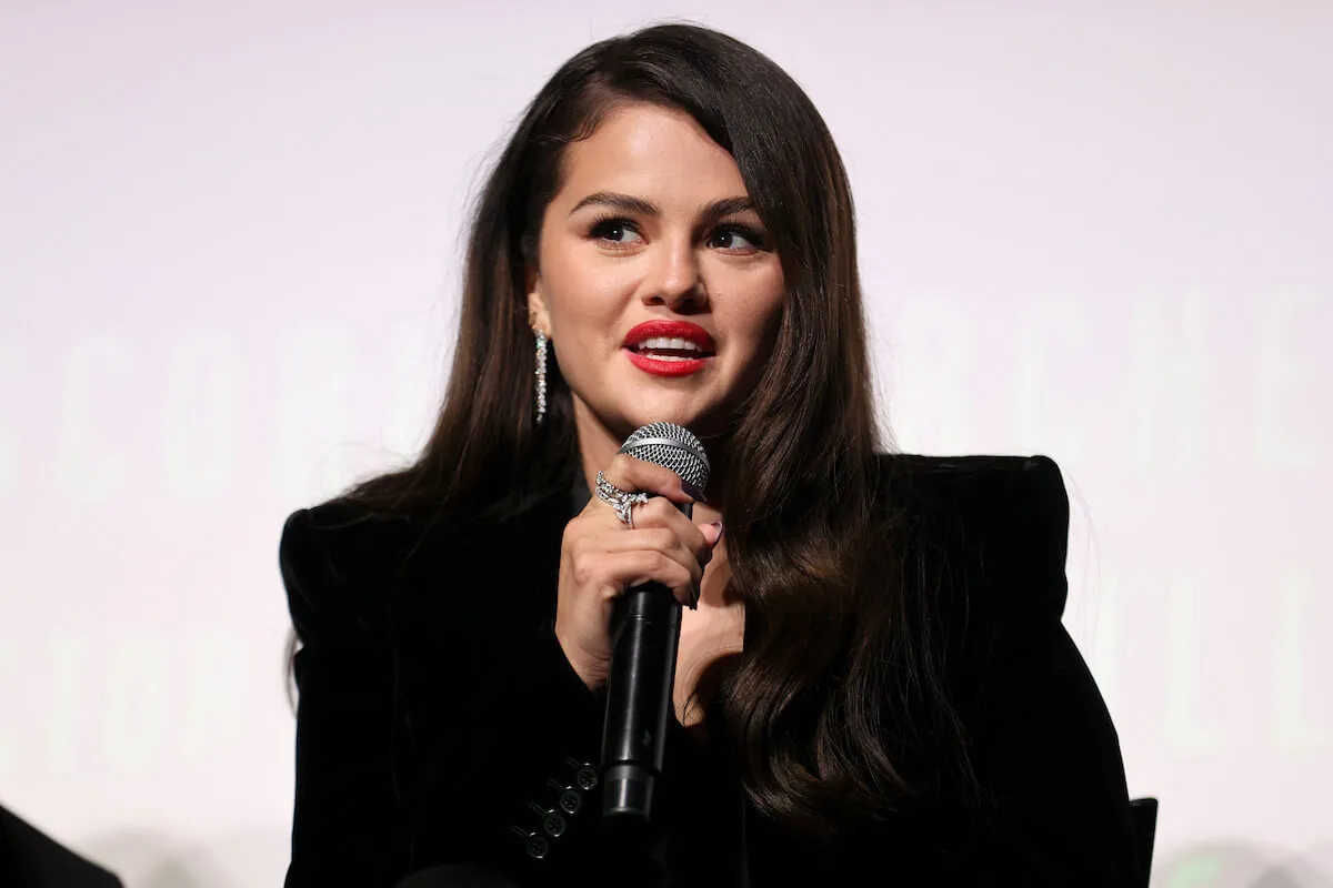 Selena Gomez, who responded to critics about not being to carry her own children,' holds a microphone