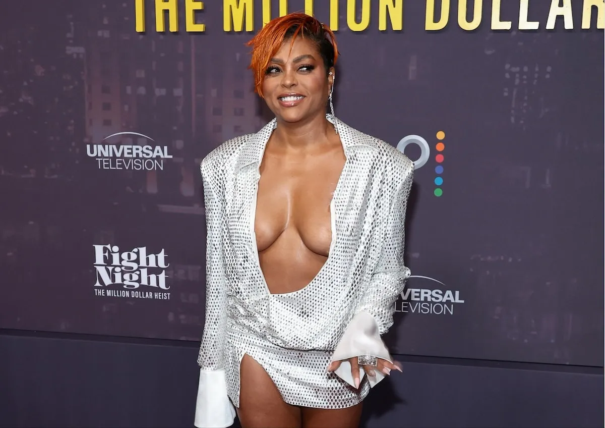 Wearing a silver plunging mini dress, Taraji P. Henson smiles for cameras on the red carpet at the world premiere of Peacock's Fight Night: The Million Dollar Heist