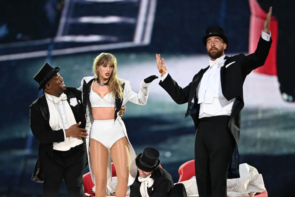 Taylor Swift and Travis Kelce, whom some fans think can be heard laughing in behind-the-scenes 'Fortnight' music video footage, onstage