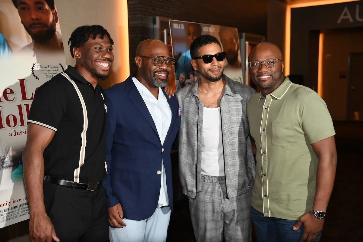 Wearing a plaid jacket and pants, Jussie Smollett stands with his guests attend the Atlanta premiere of "The Lost Holliday"