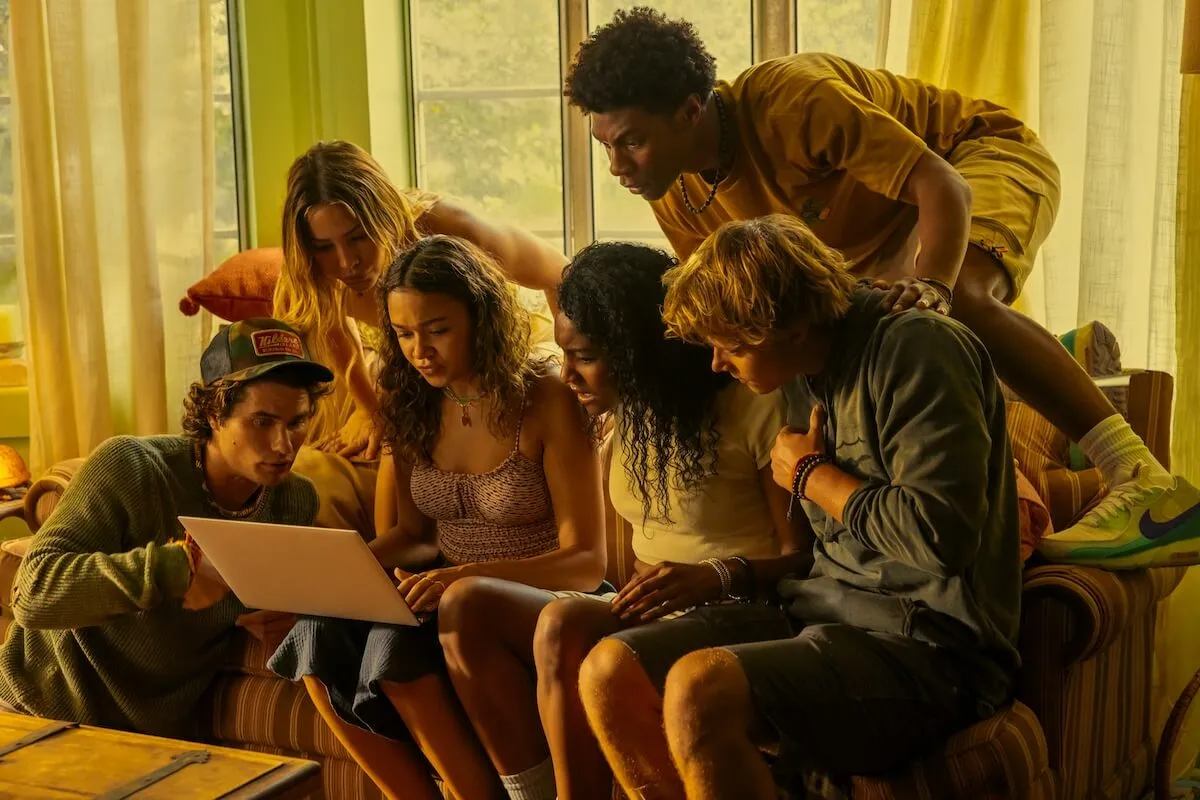 The 'Outer Banks' cast sits on a couch in a scene from Season 4, which premieres in two parts