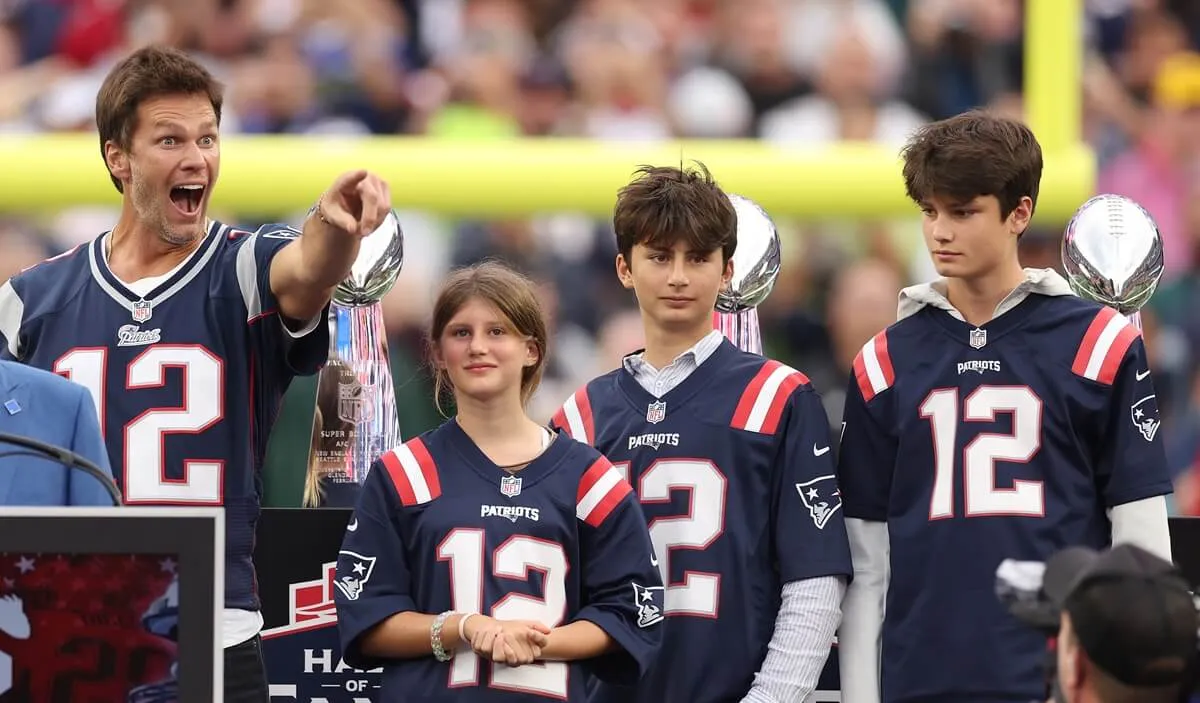 Tom Brady points towards the crowd while his children, Vivian, Benjamin, and Jack, look on during a ceremony honoring their dad