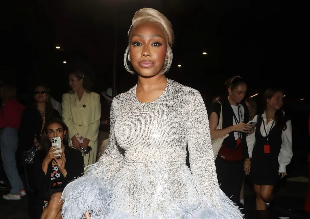 Wearing a silver sequin dress and platinum blonde hair, Yung Miami poses for photos at the Christian Cowan S/S25 Runway Show