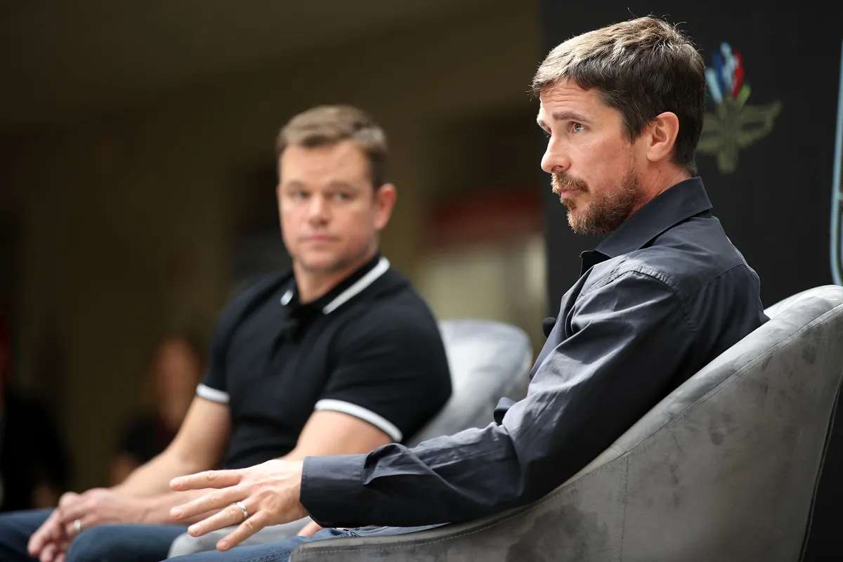 Matt Damon and Christian Bale talking at a press conference.