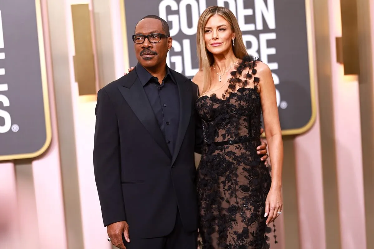 Eddie Murphy posing alongside Paige Butcher at the 80th Annual Golden Globe Awards as they wear matching-colored outfits.