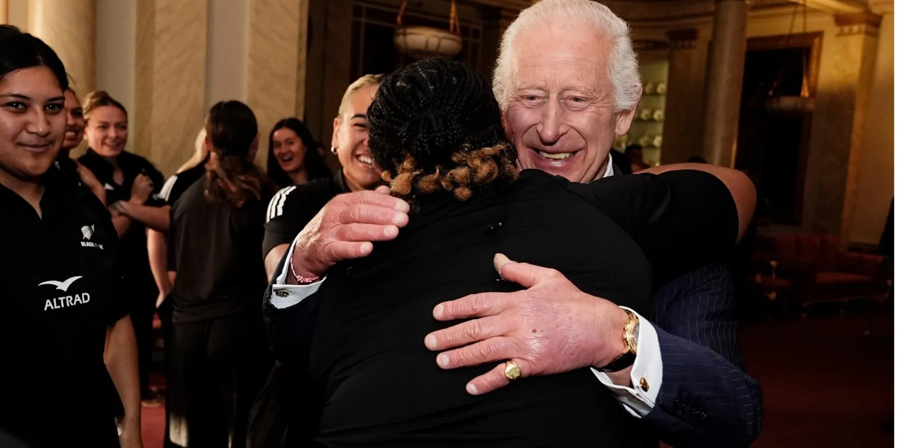 King Charles hugs a member of New Zealand's Black Ferns rugby union team at Buckingham Palace on September 11, 2024.