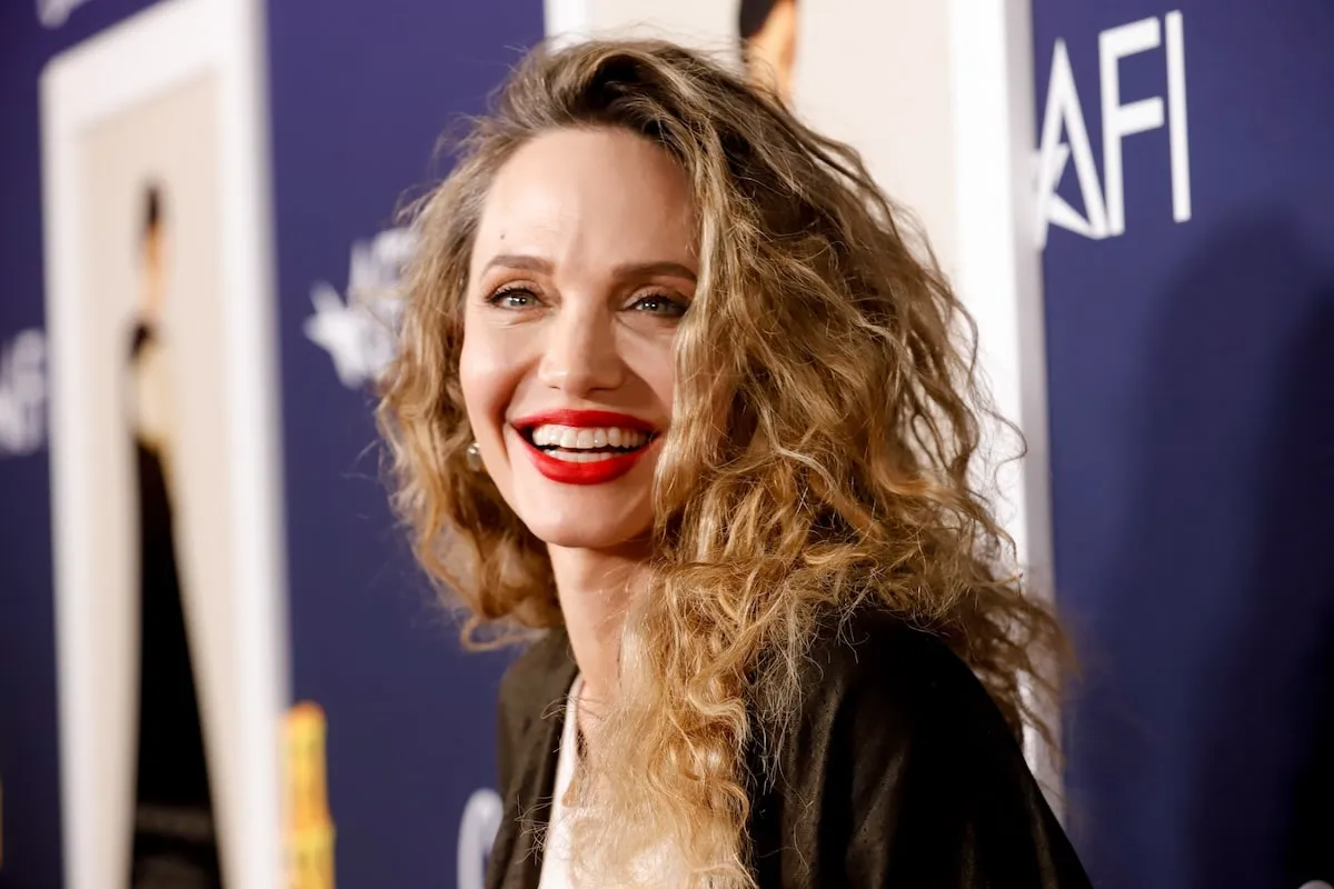 Wearing red lipstick and a curly hairstyle, Angelina Jolie smiles broadly at the 'Maria' screening at AFI Fest