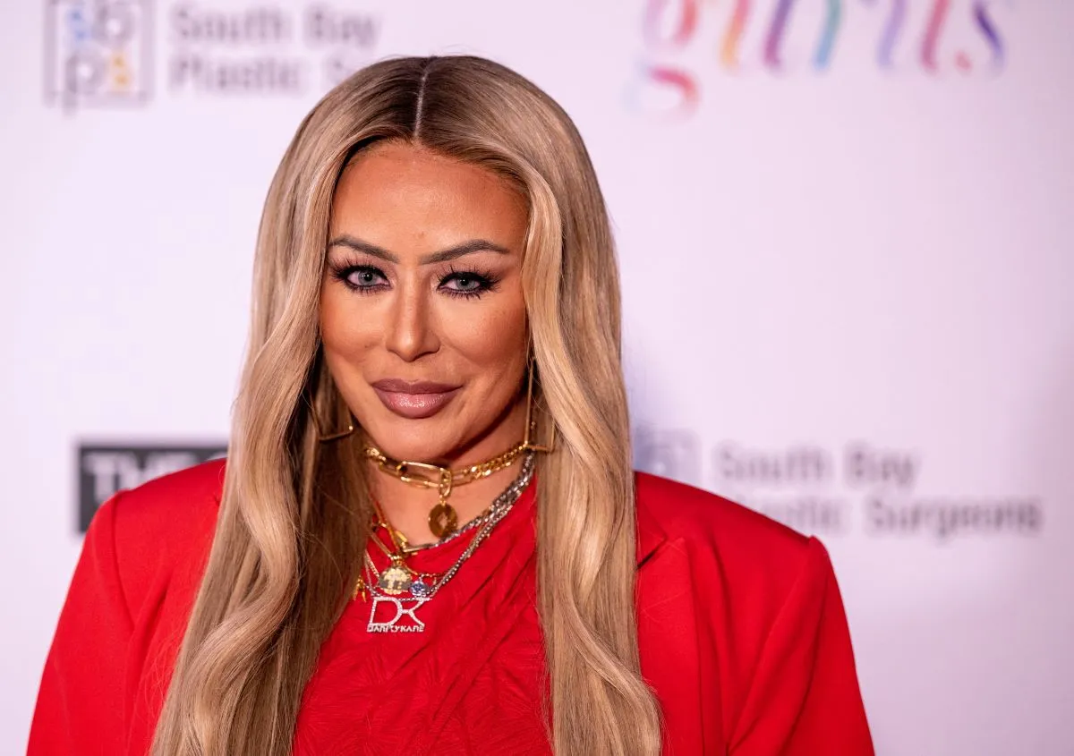 Aubrey O'Day wears a red shirt and necklaces.