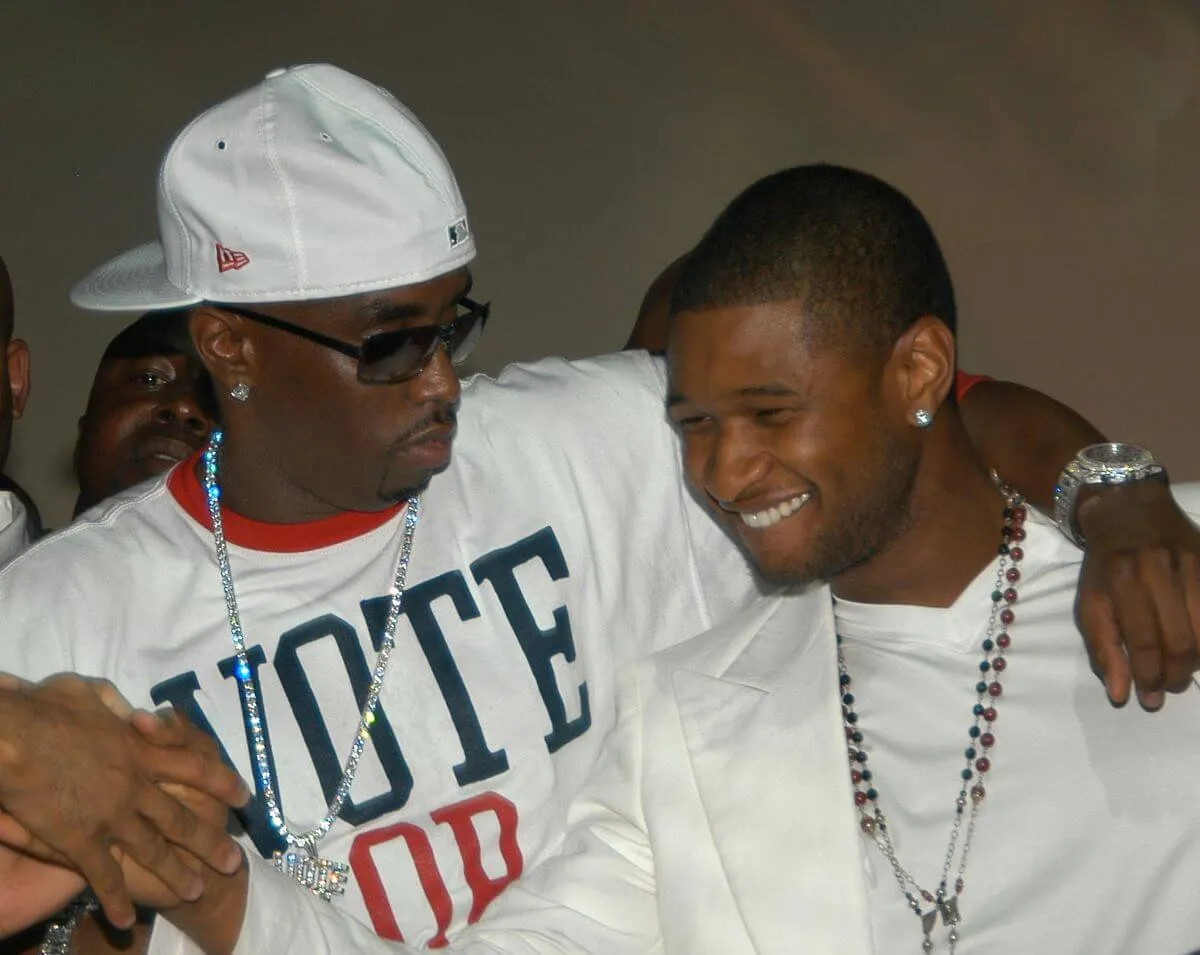 Sean 'Diddy' Combs wears a baseball hat and sunglasses. He stands with his arm around Usher. They both wear white.