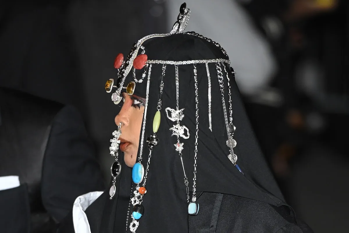 Wearing a black coat, dress, and headpiece, Erykah Badu poses for photos at the CFDA Fashion Awards 2024