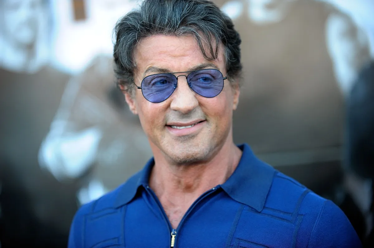 Sylvester Stallone posing in a blue shirt and shades at 'The Expendables' screening.