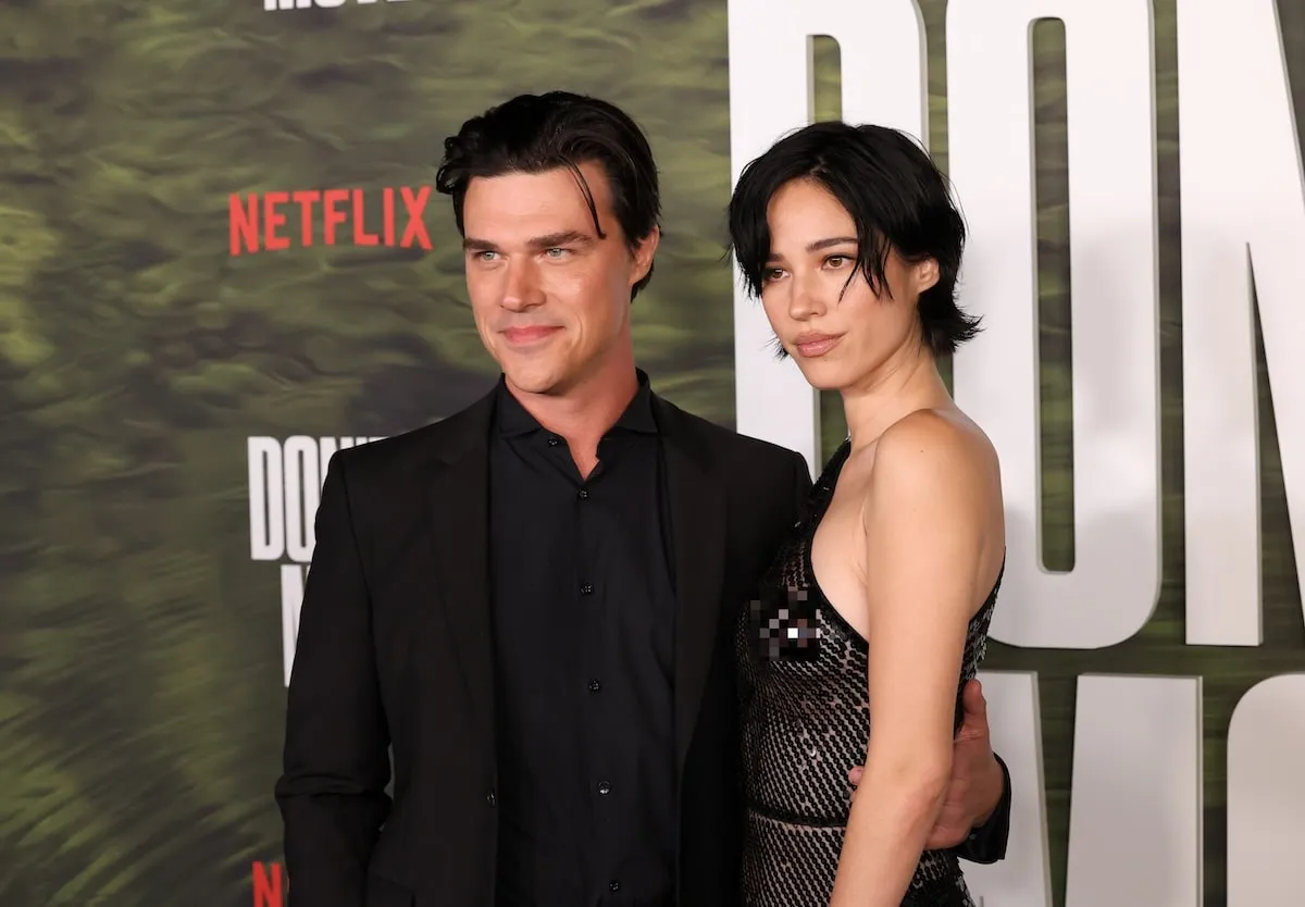 Wearing a black sheer dress, Kelsey Asbille smiles with Finn Wittrock on the red carpet of the Don't Move photo call