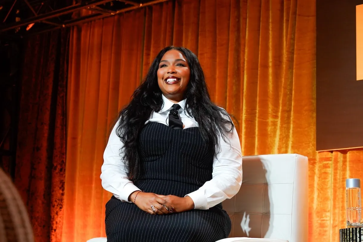 Singer Lizzo wears a black pencil dress and white shirt while speaking onstage at Fortune's Most Powerful Women Summit