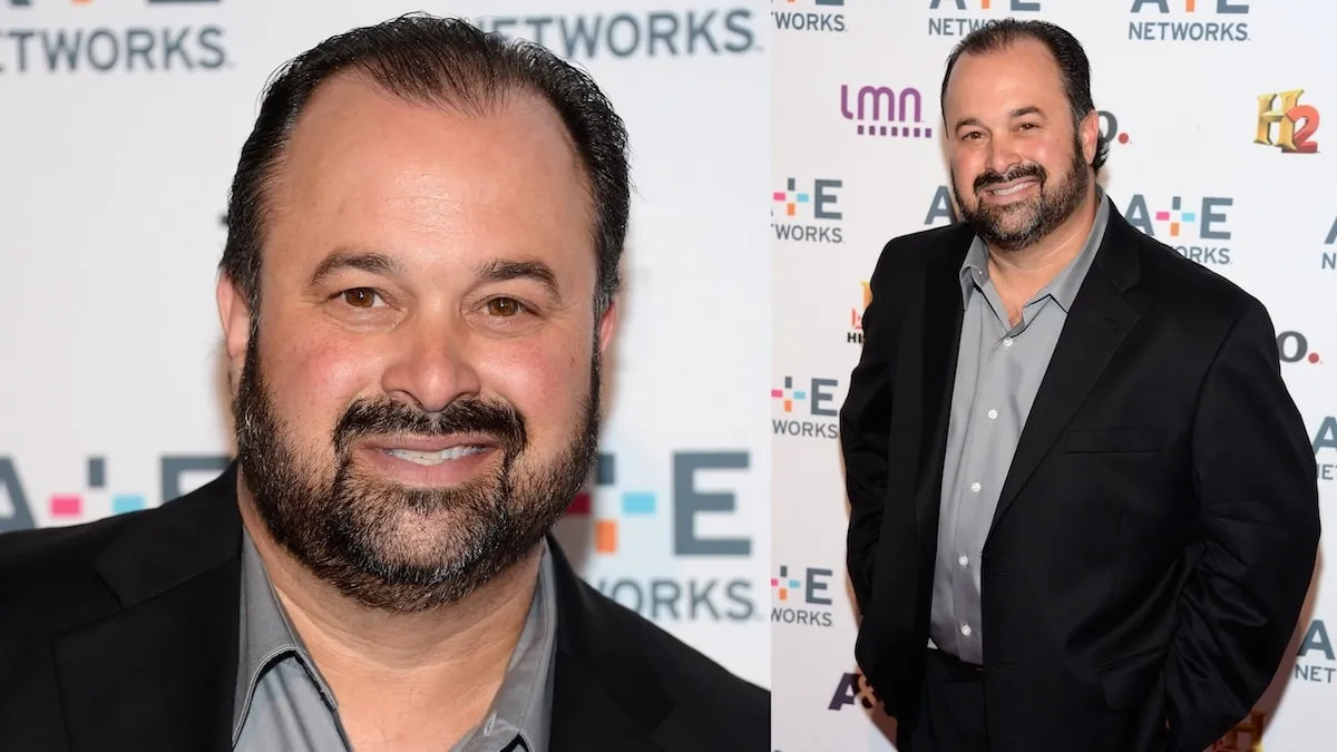 Wearing a black suit and gray button-up, Frank Fritz of American Pickers stands on a red carpet in 2012