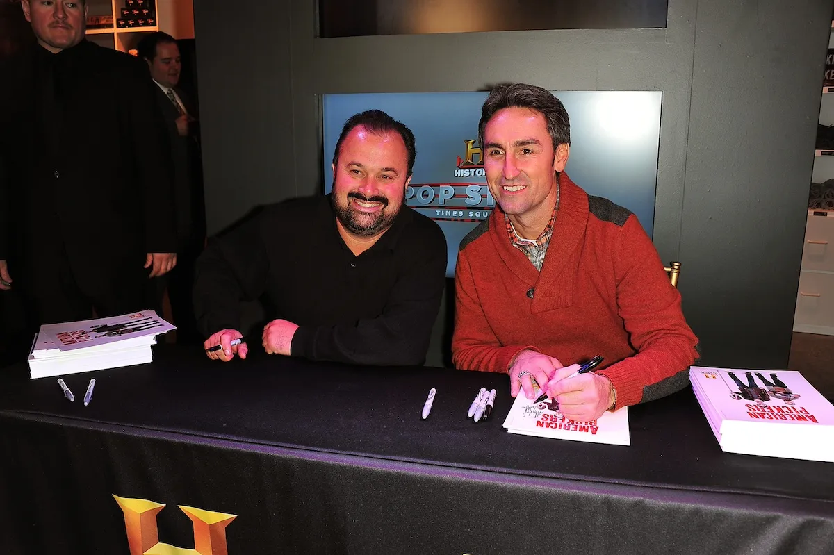 Frank Fritz and Mike Wolfe of 'American Pickers' sitting at a table and signing autographs for fans