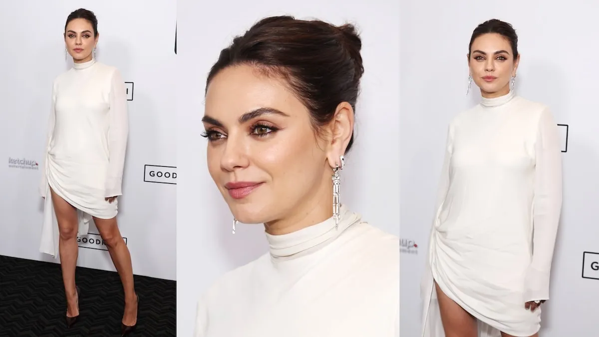 Wearing a white dress, Mila Kunis smiles as she stands alone on the red carpet for 'Goodrich'