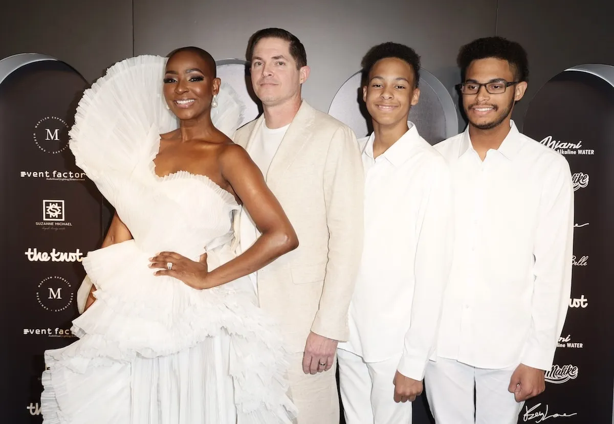 Wearing all white, Guerdy Abraira smiles with her husband and two sons at her celebration of life party