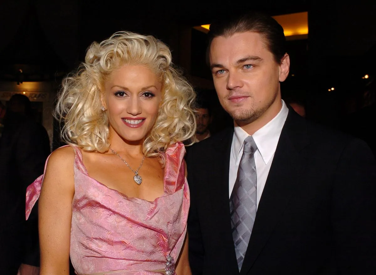 Gwen Stefani wears a pink dress and stands with Leonardo DiCaprio, who wears a suit.