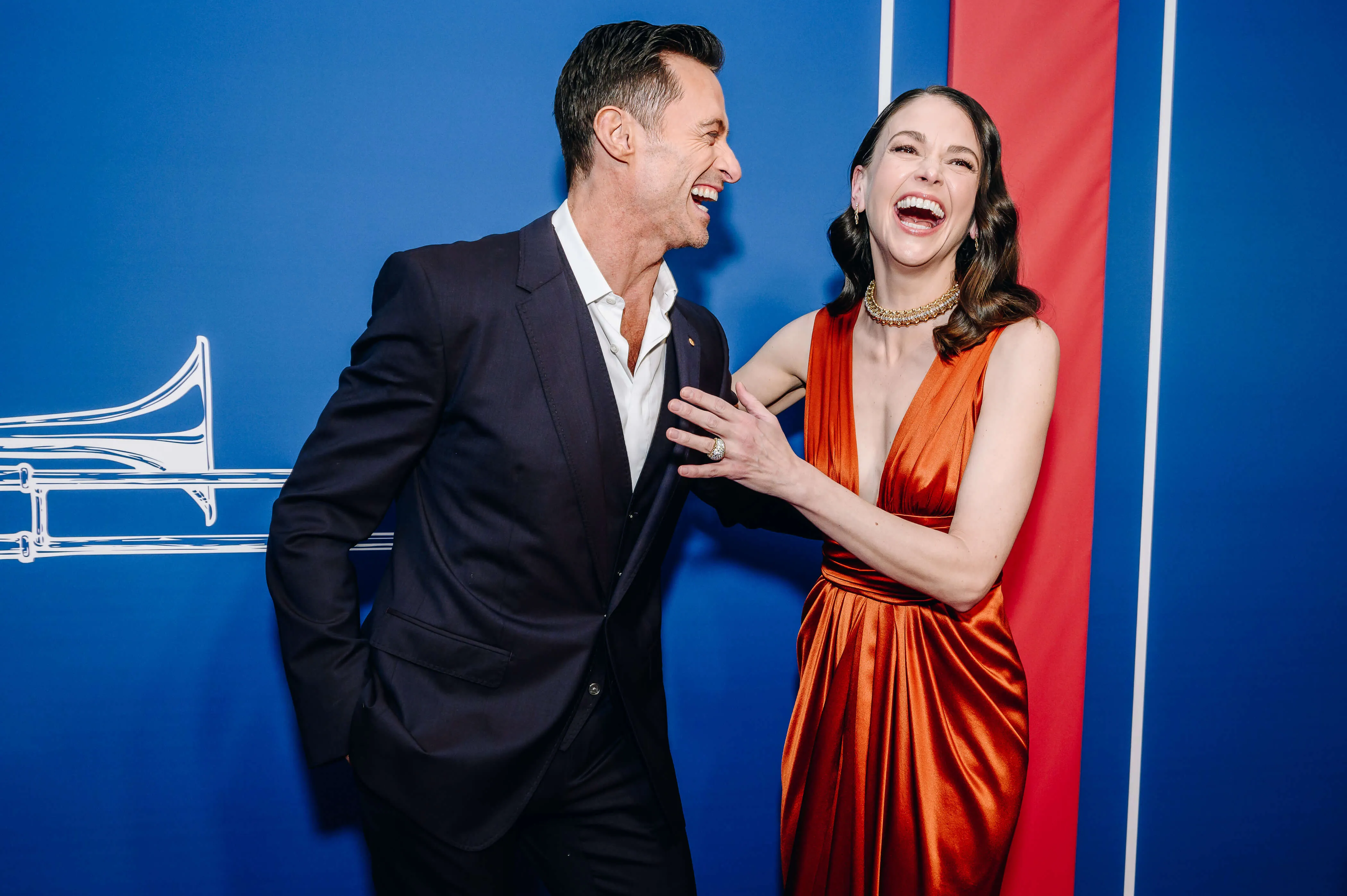 Hugh Jackman and Sutton Foster at 'The Music Man' Broadway opening. Jackman is leaning into Foster and laughing while Foster is reaching toward Jackman and also laughing.