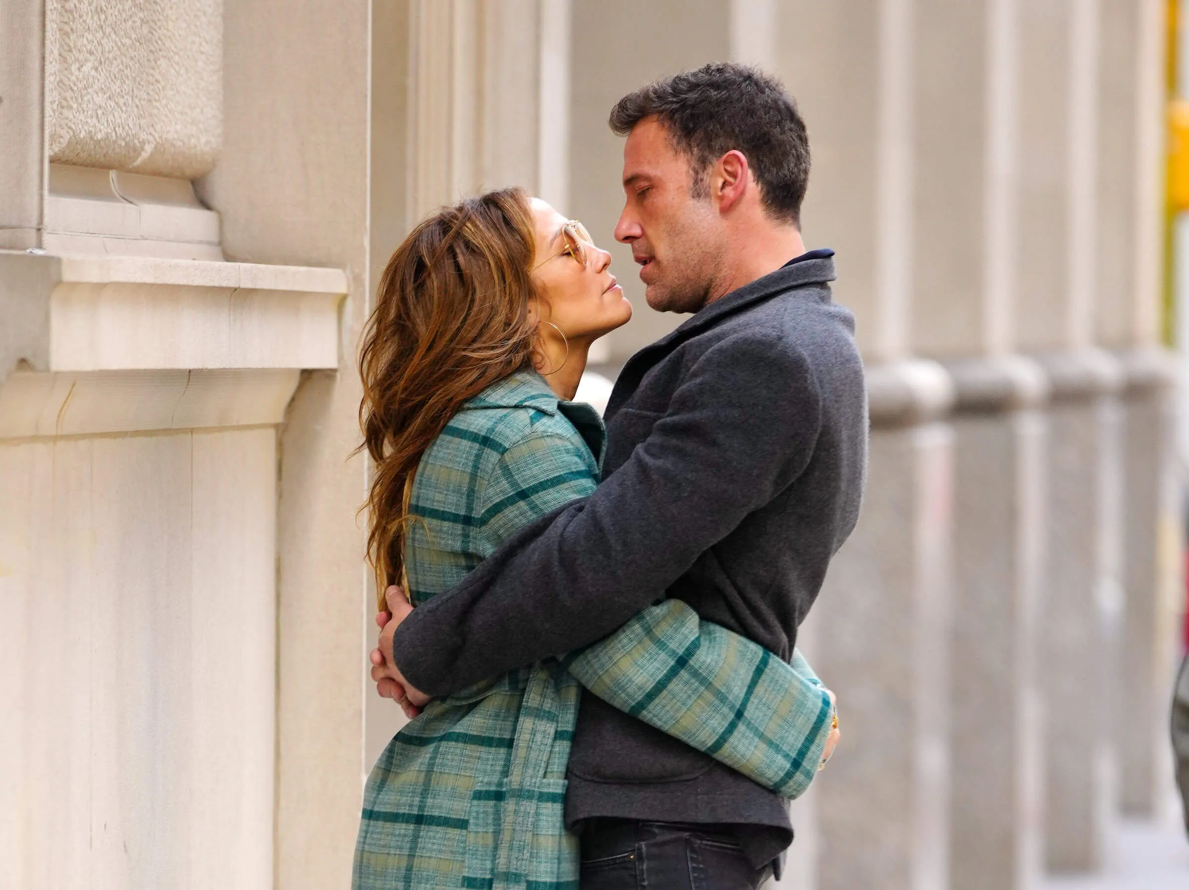 Jennifer Lopez and Ben Affleck embracing in New York City in 2021. Lopez is wearing a green plaid jacket and Affleck is wearing a gray jacket.