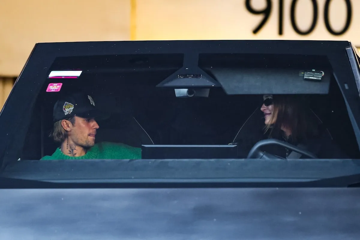 Driving their Tesla Cybertruck, Justin Bieber and Hailey Bieber look for traffic as they exit a parking garage in LA