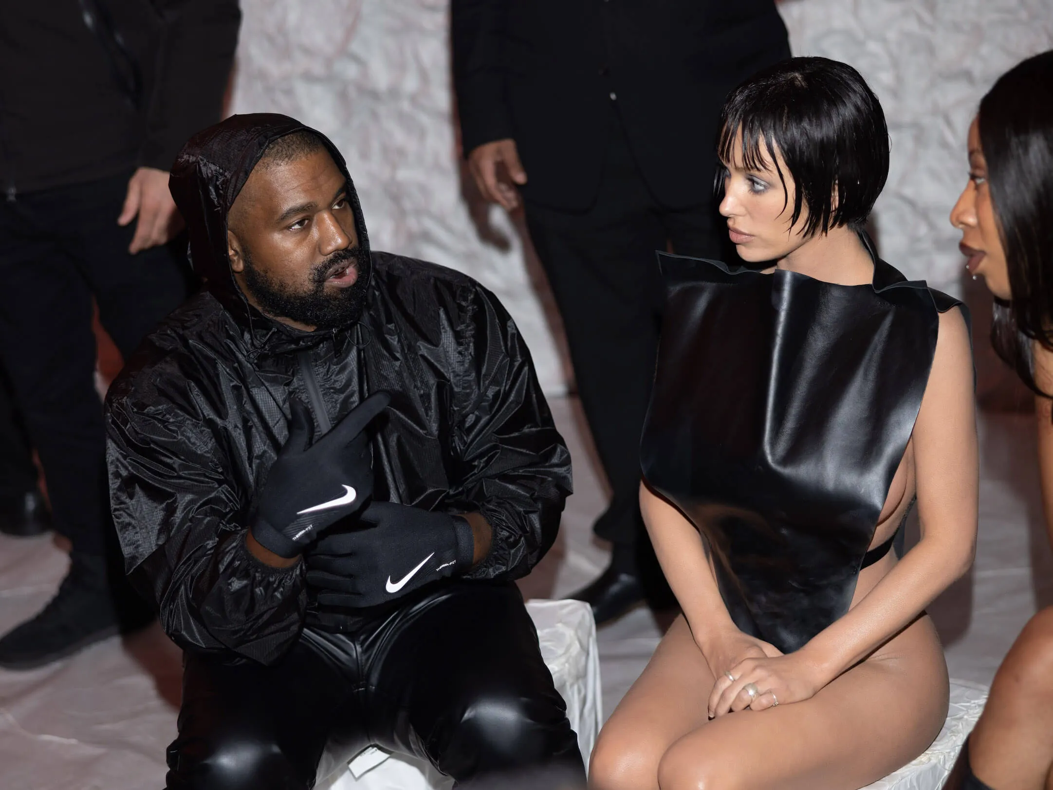 Kanye West and Bianca Censori sitting next to each other in all-black outfits at a fashion show