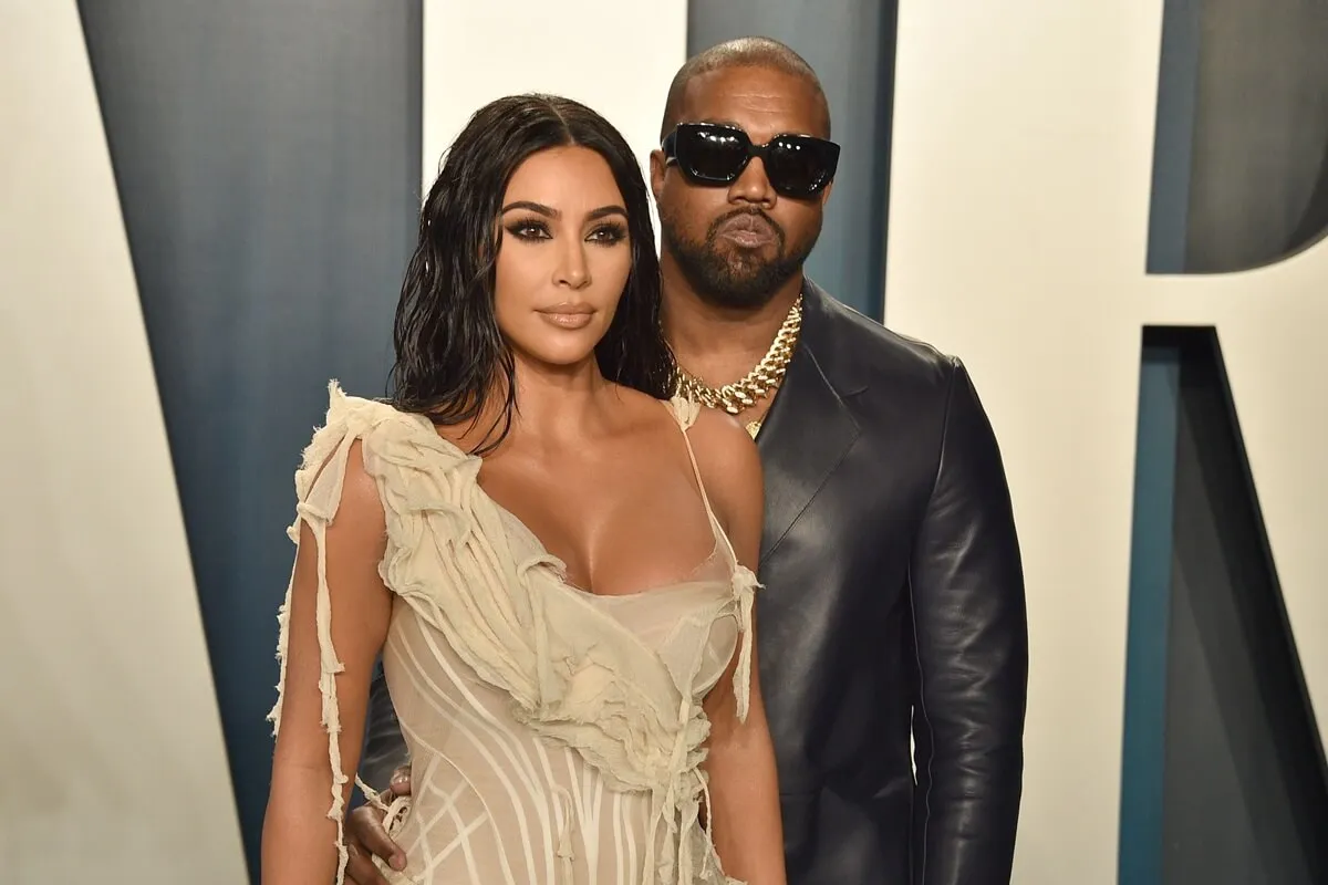 Kim Kardashian and Kanye West attend the 2020 Vanity Fair Oscar Party while wearing a tan dress and black leather jacket respectively.