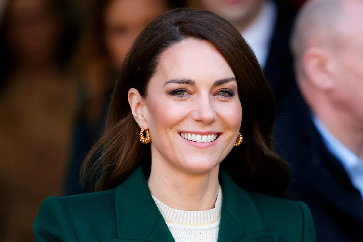 Kate Middleton smiles wearing a green coat.