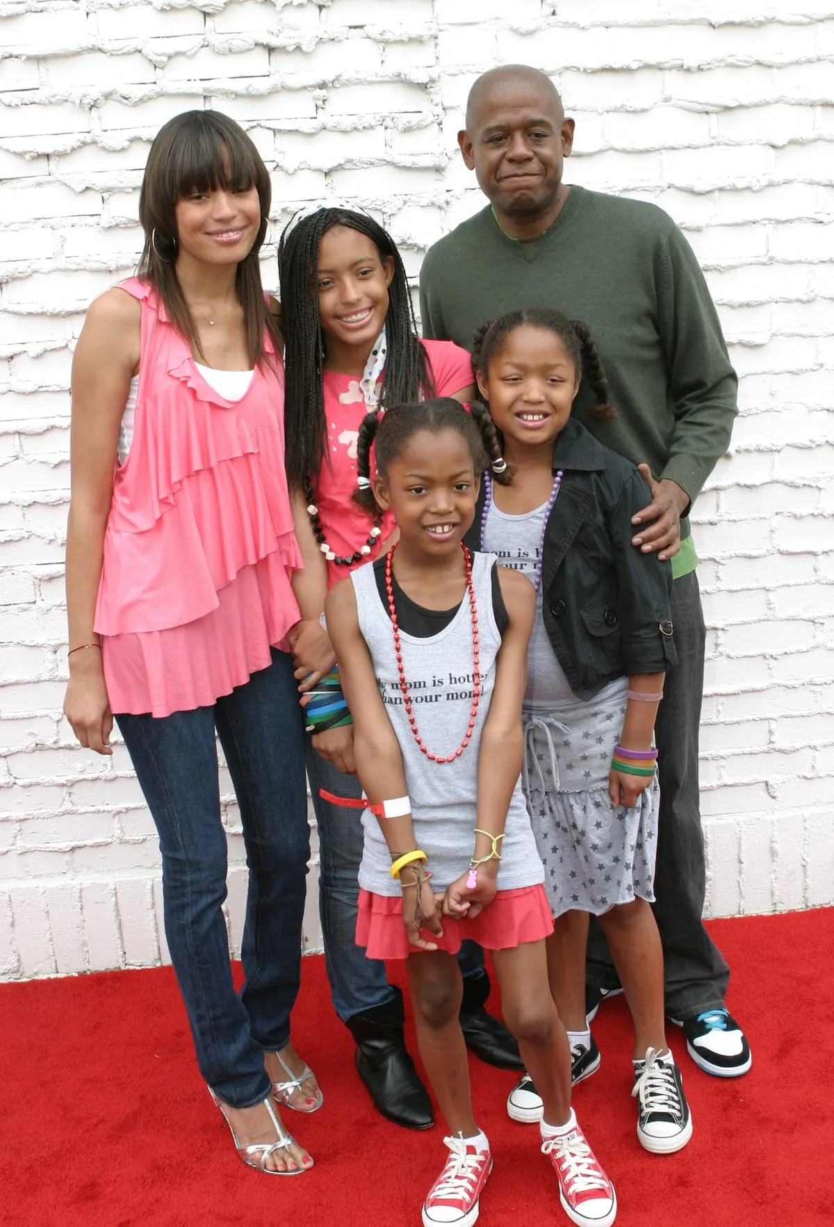 Forest Whitaker stands on the red carpet and smiles with his family, including wife Keisha and daughters, True, Autumn, and Sonnet, in 2011