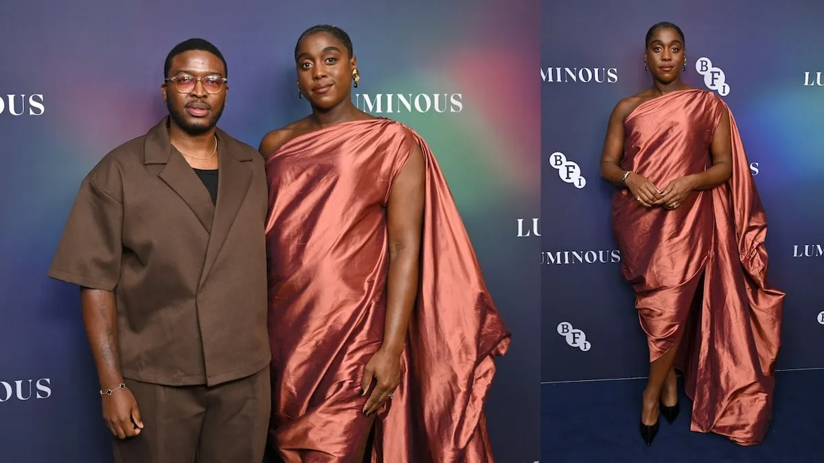 Wearing a red-orange satin gown, Lashana Lynch stands with her husband on the red carpet