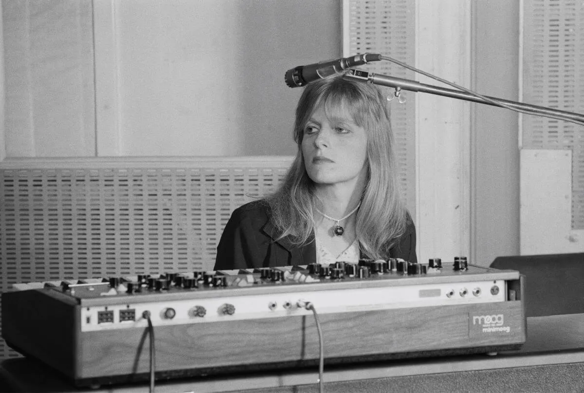 A black and white picture of Linda McCartney sitting behind a keyboard.