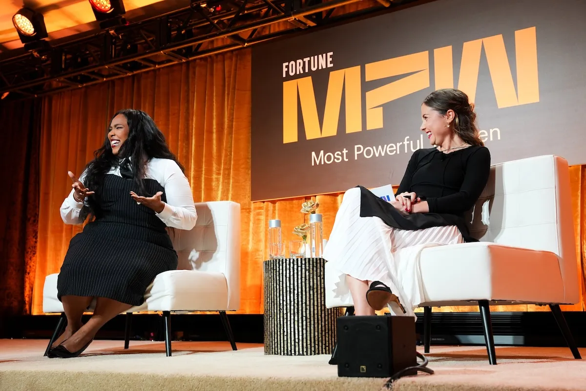 Singer Lizzo wears a black pencil dress and white shirt while speaking onstage at Fortune's Most Powerful Women Summit