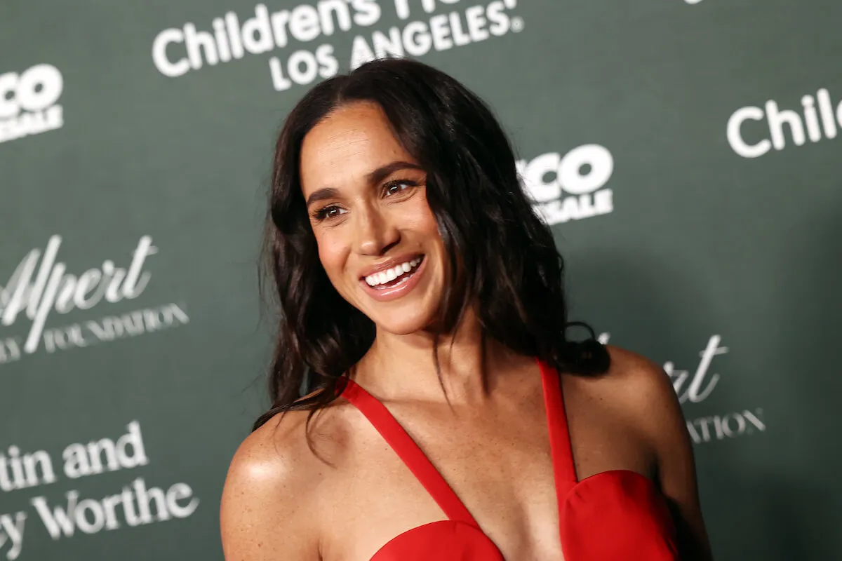 Meghan Markle, who has a 'weapon' in her journal to use against the royal family, smiles wearing a red gown