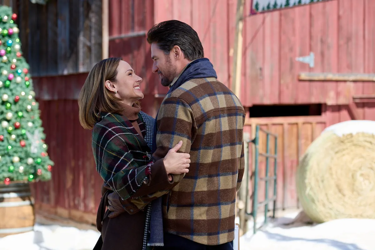 Woman and man embracing in front of a faded red barn