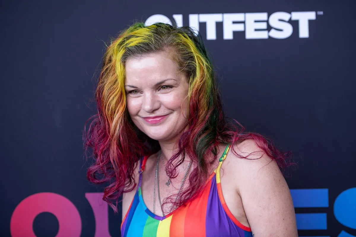 Pauley Perette with brightly colored hair and wearing a rainbow-striped dress