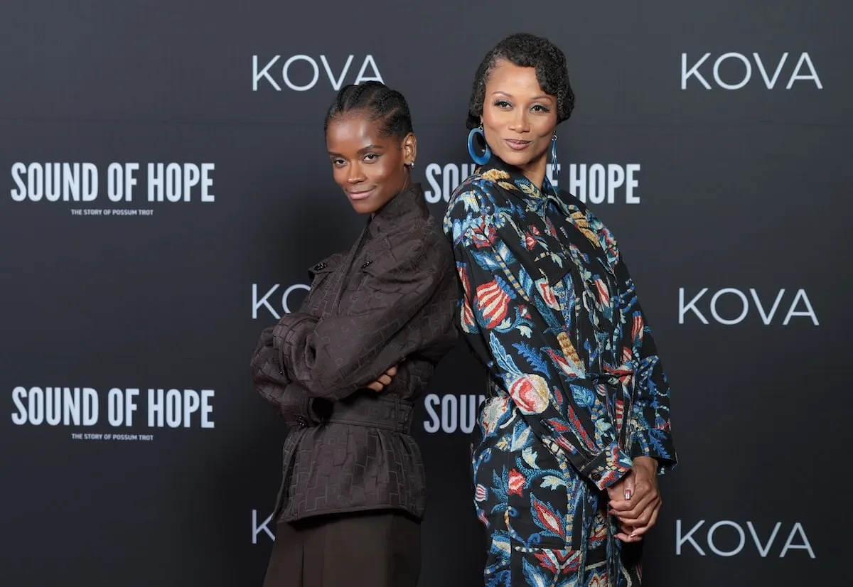 Possum Trot co-stars Letitia Wright, wearing a brown suit, and Nika King, wearing a flowery jumpsuit, stand together on the red carpet