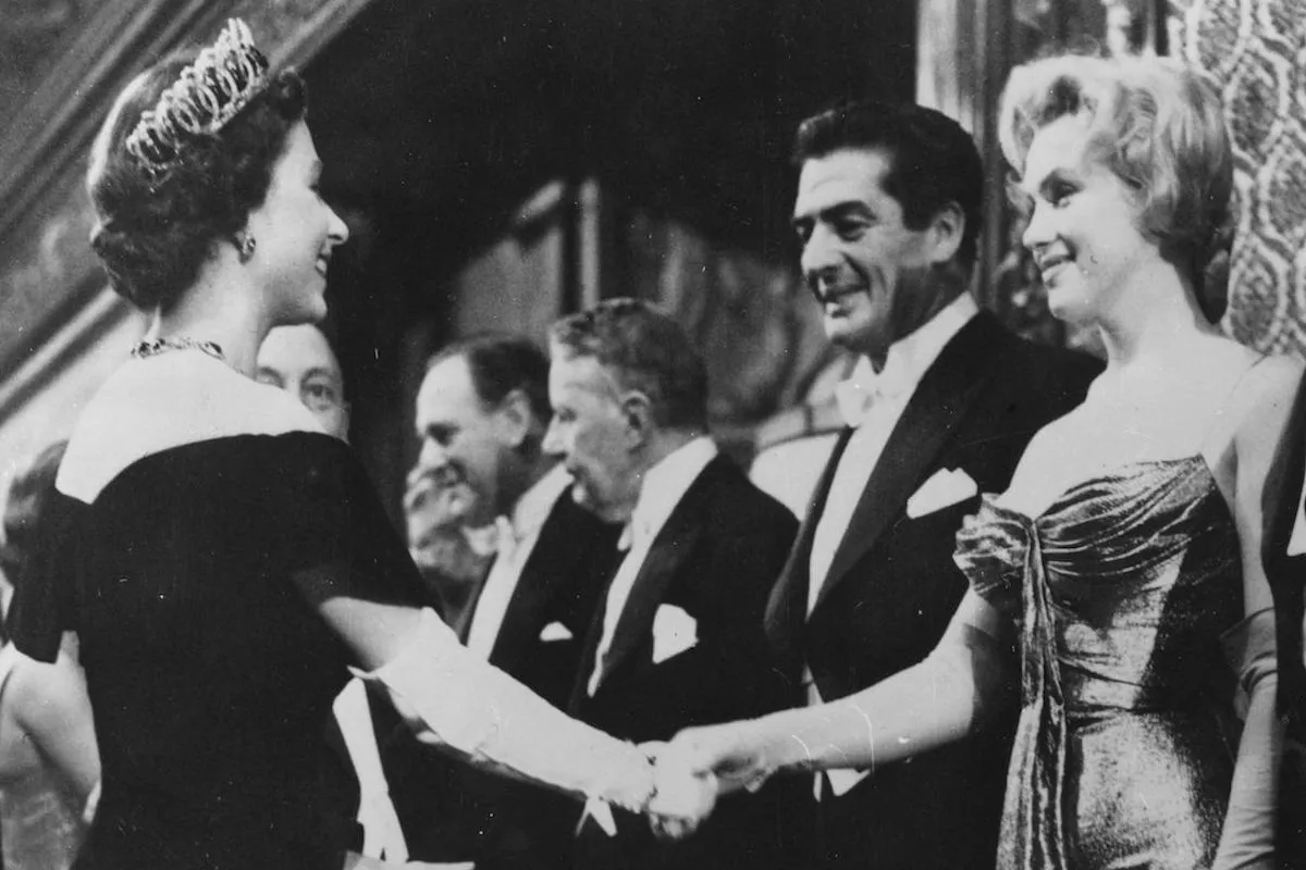 Queen Elizabeth II and Marilyn Monroe shake hands.