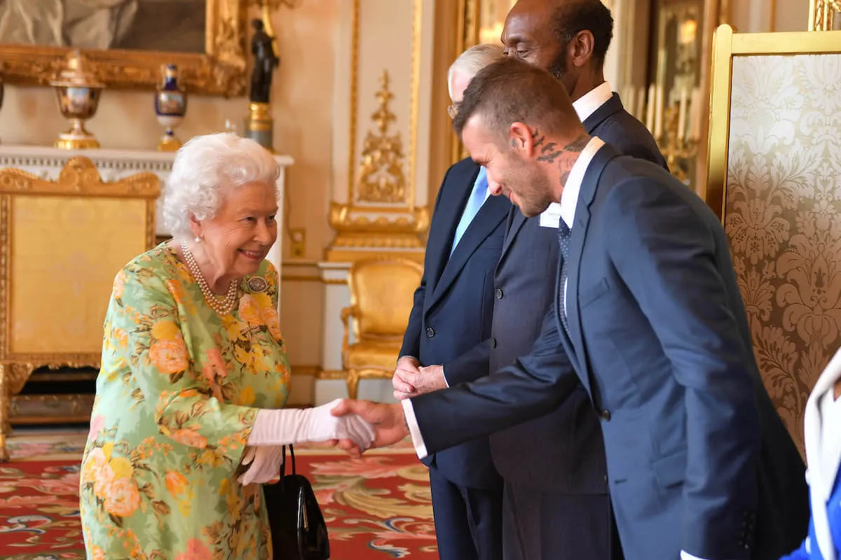 Queen Elizabeth II, whom a former aide called a 'shy person,' shakes hands with David Beckham