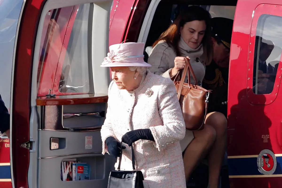 Queen Elizabeth II, whom former aide Samantha Cohen described as a 'shy person,' exits a helicopter with Samantha Cohen