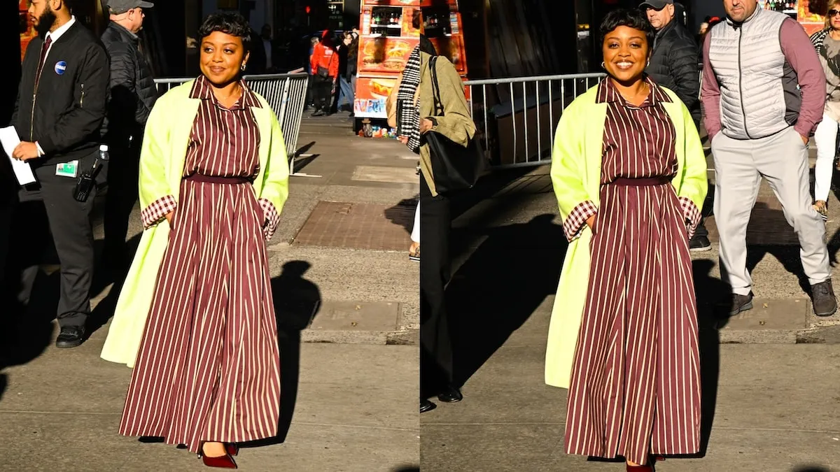 Wearing a striped jumpsuit and neon cardigan, Quinta Brunson smiles at cameras outside of ABC Studios