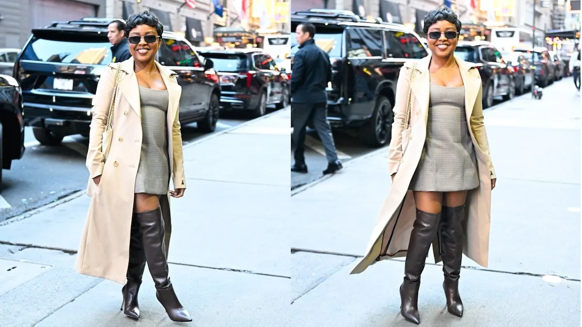 Wearing a beige trench coat and plaid mini dress, Quinta Brunson waves to cameras outside of ABC Studios