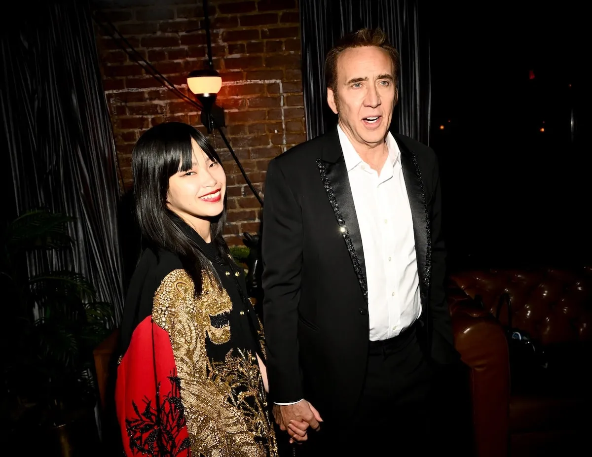 Smiling and holding hands, Riko Shibata and Nicolas Cage at "Longlegs" Los Angeles premiere