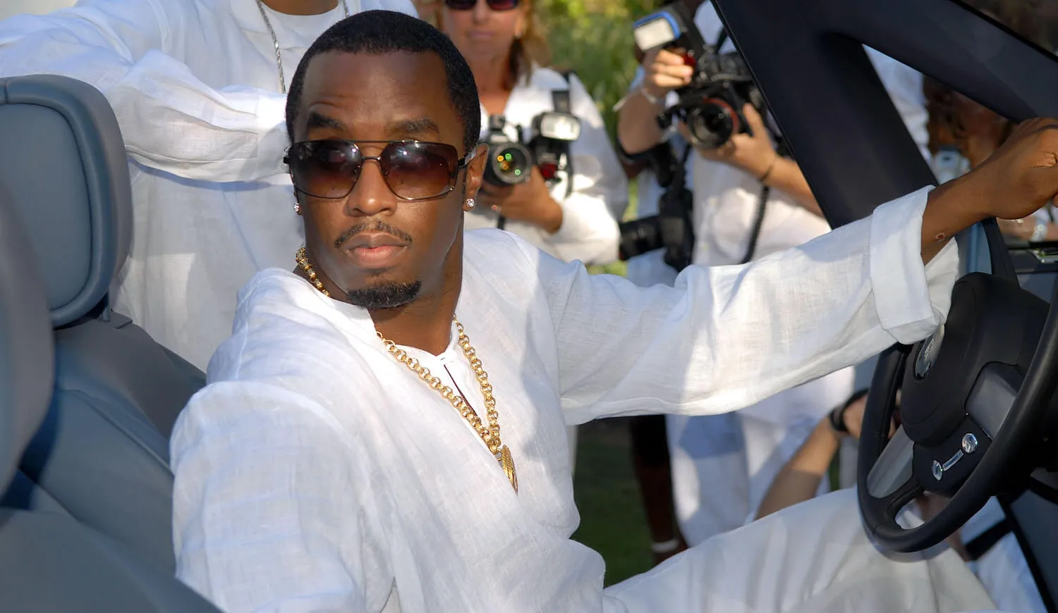 Sean 'Diddy' Combs dressed in white for a White Party in 2007. He's driving a car and looking over his shoulder.