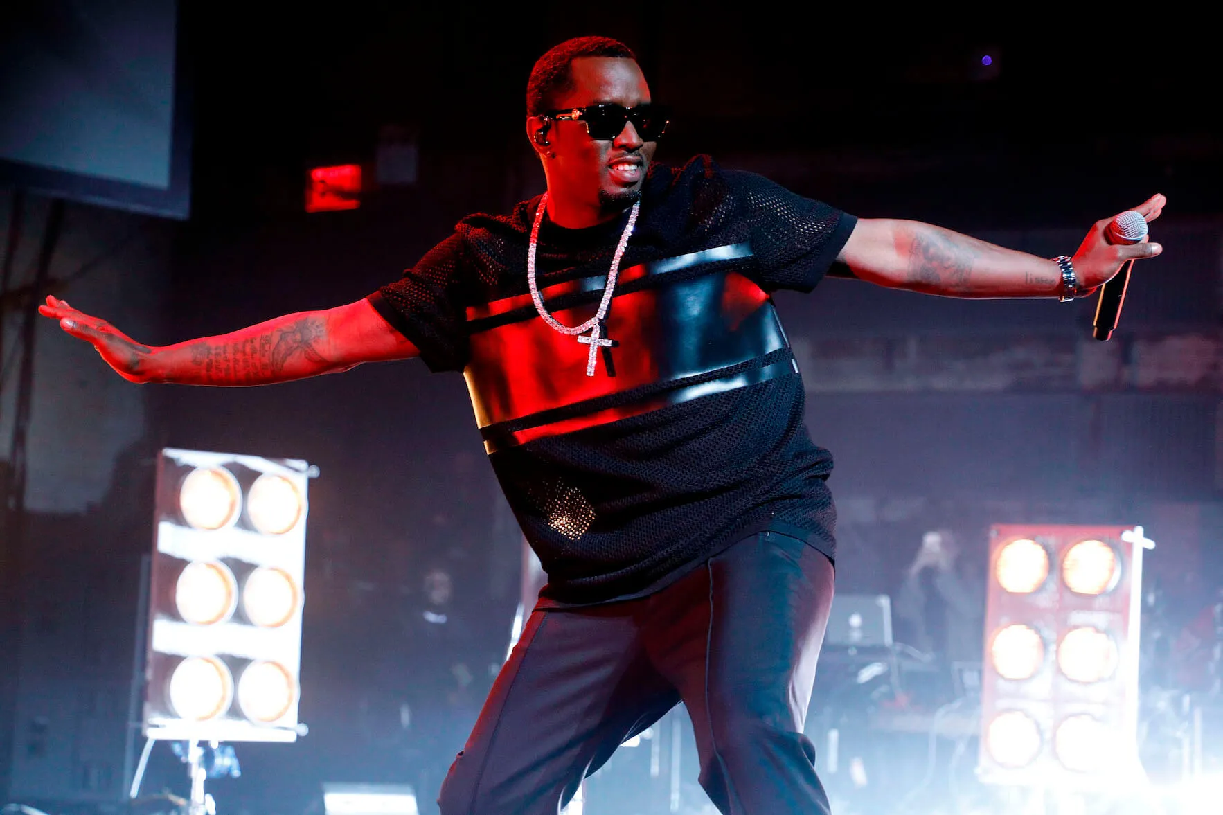 Sean 'Diddy' Combs performing on stage in 2017. He has his arms out to the side and is wearing a black T-shirt and sunglasses.