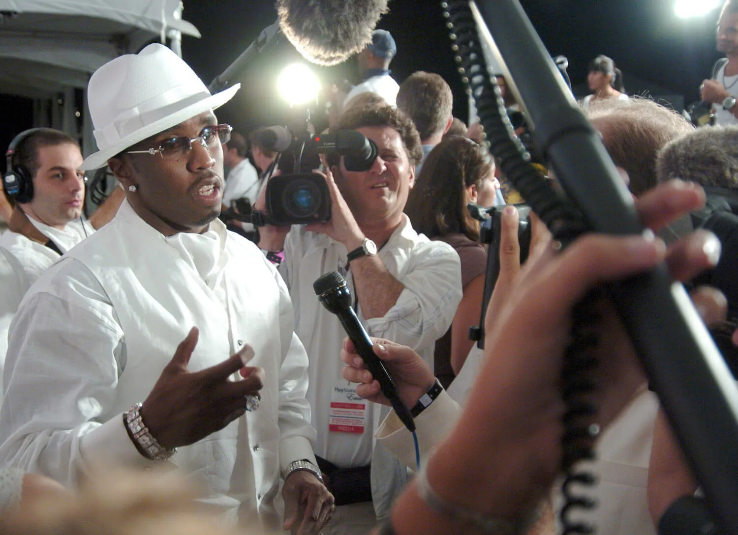 Sean 'Diddy' Combs wearing a white outfit and hat while speaking to reporters also wearing white.