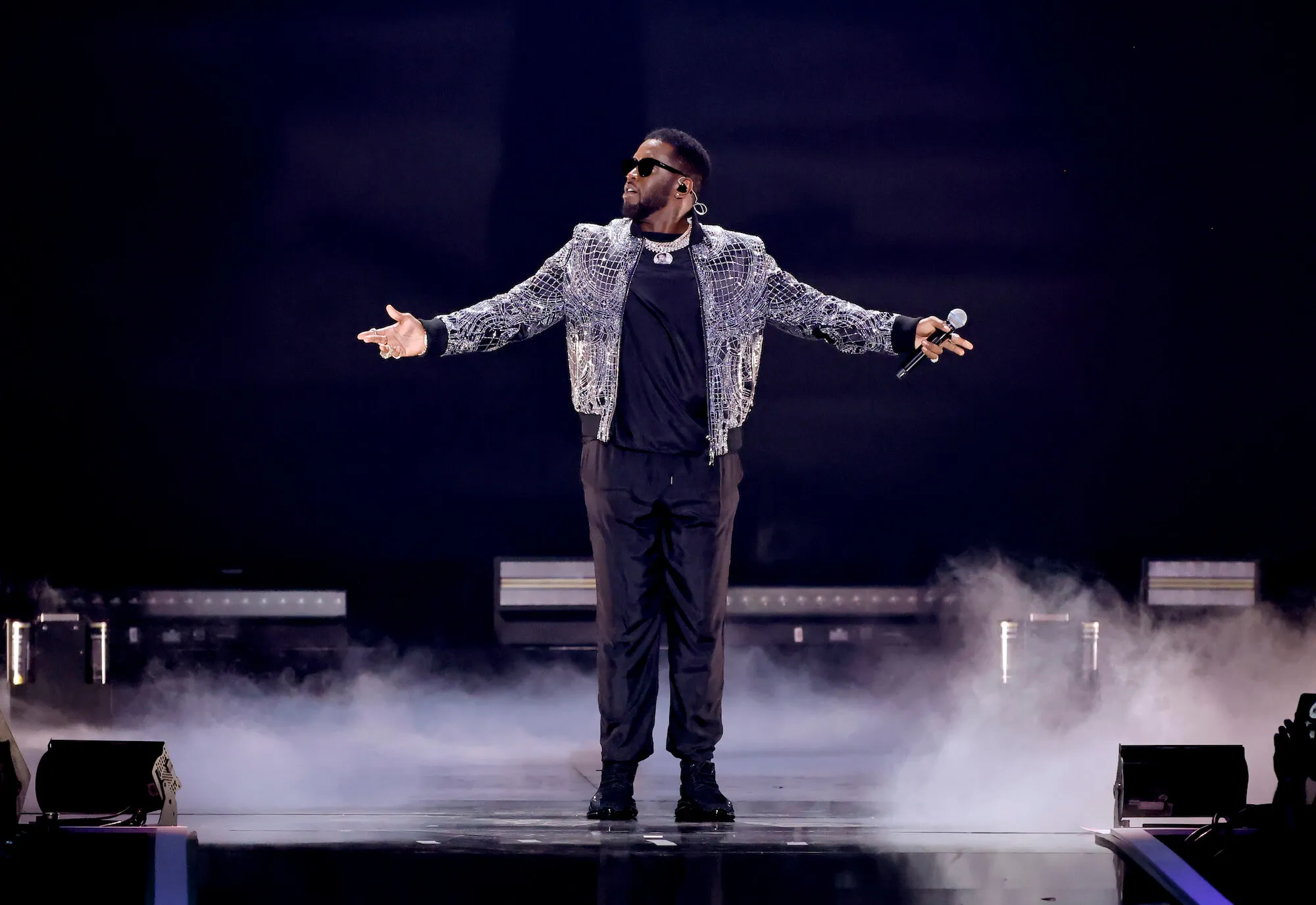 Sean 'Diddy' Combs performing on stage with his arms outstretched. He's wearing a fringe diamond jacket.