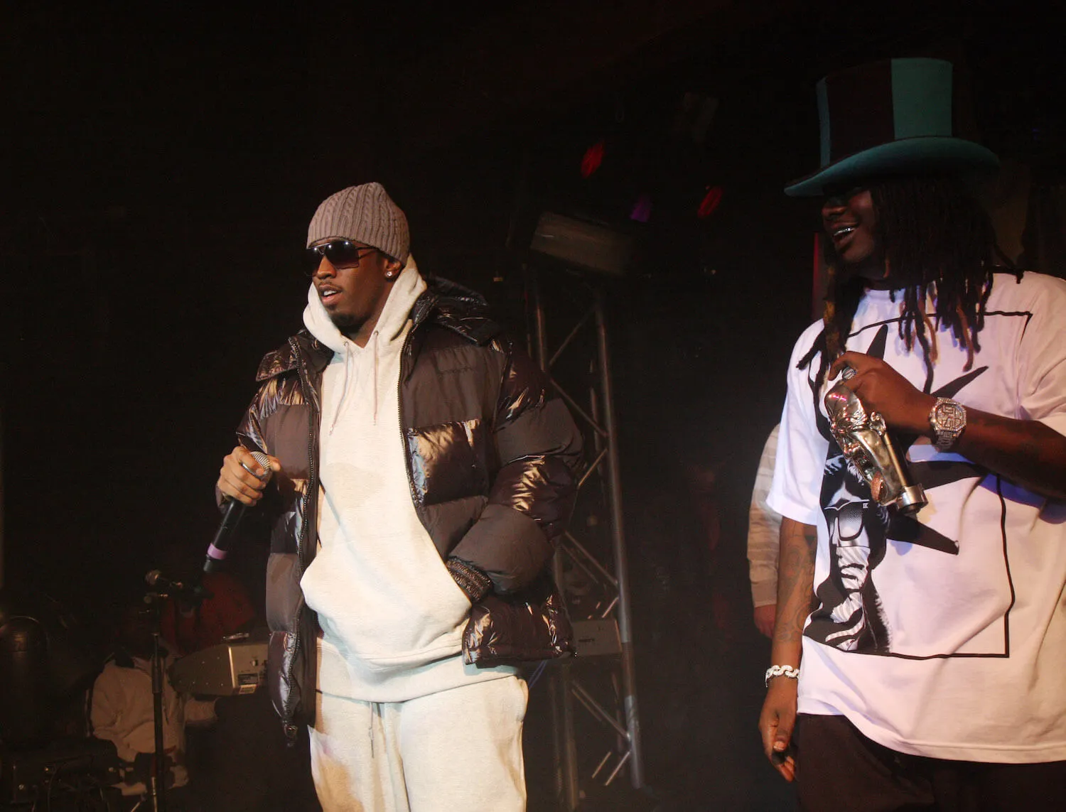 Sean 'Diddy' Combs and T-Pain next to each other on stage in 2008. Combs is wearing a coat over a hoodie and T-Pain is wearing a short-sleeve shirt and a top hat.