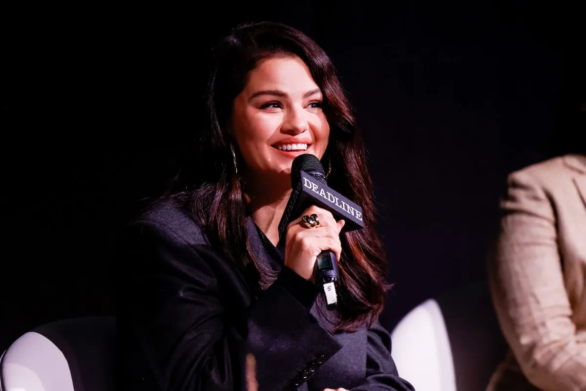 Wearing a black suit, Selena Gomez speak on a panel for 'Emilia Pérez' at Deadline Contenders