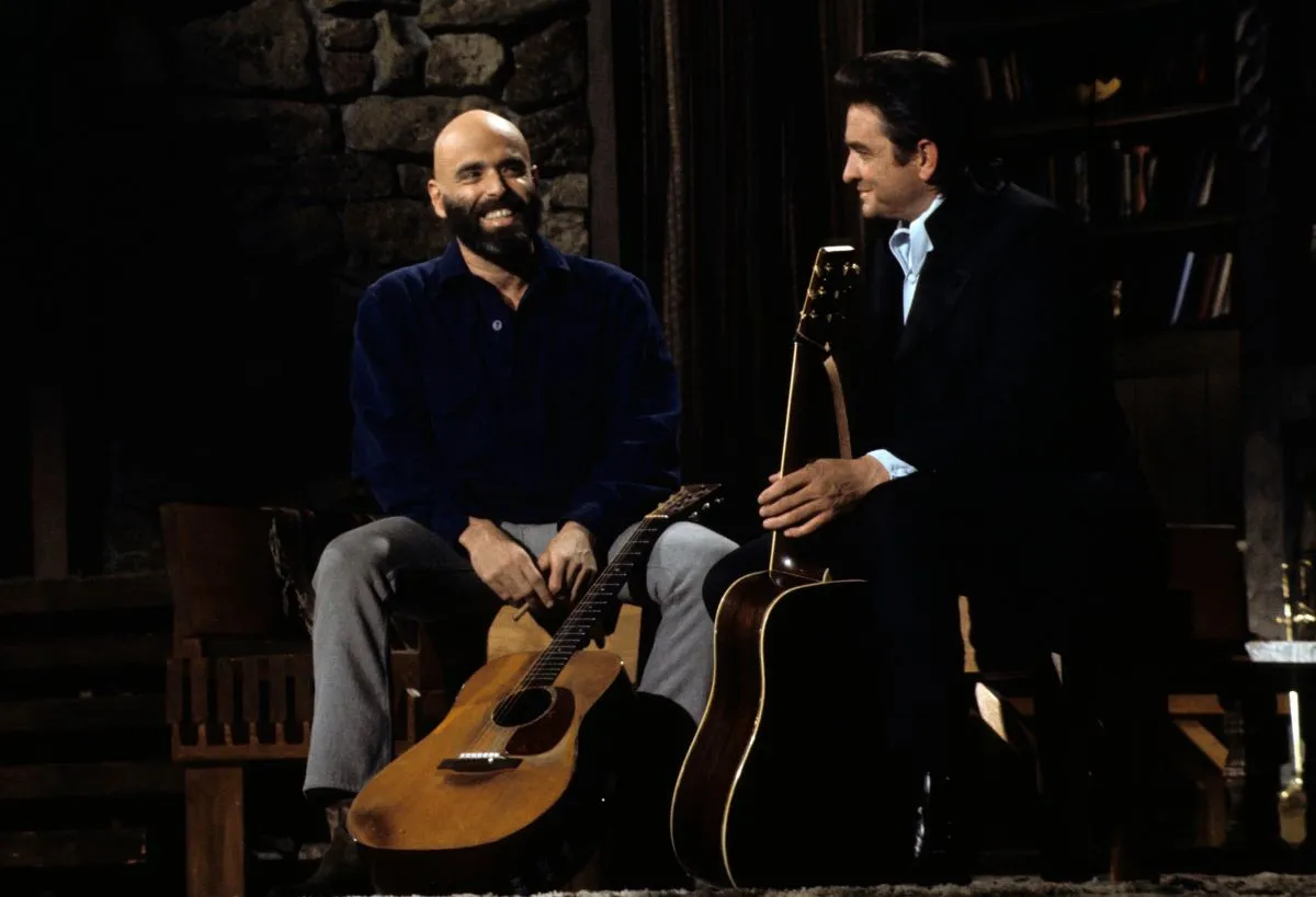 Shel Silverstein and Johnny Cash sit together. They both hold guitars.